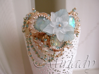 A romantic V-shaped bracelet made with Swarovski® beads, Czech glass beads and resin cabochons in shades of sand and aqua.